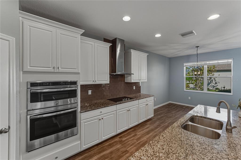 7628 Surf Reed Way Wesley Chapel, FL 33545 - Photo 14 of 76 a kitchen with granite countertop a sink stove and cabinets