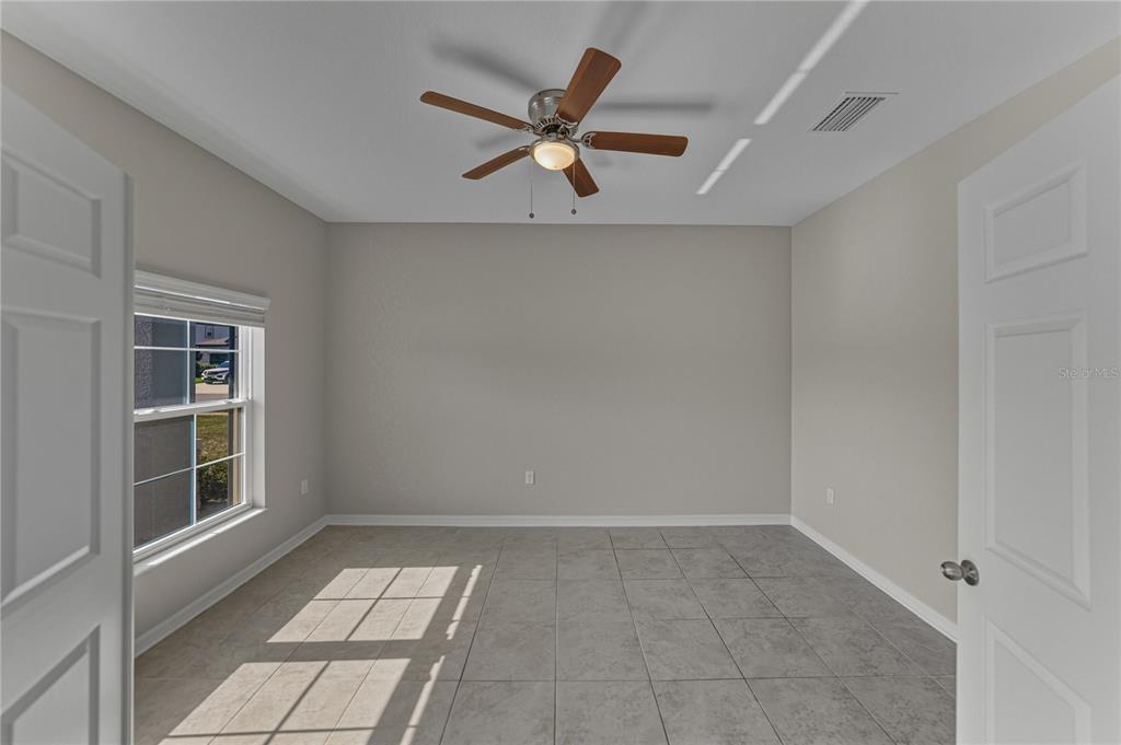 7628 Surf Reed Way Wesley Chapel, FL 33545 - Photo 21 of 76 an empty room with windows and ceiling fan