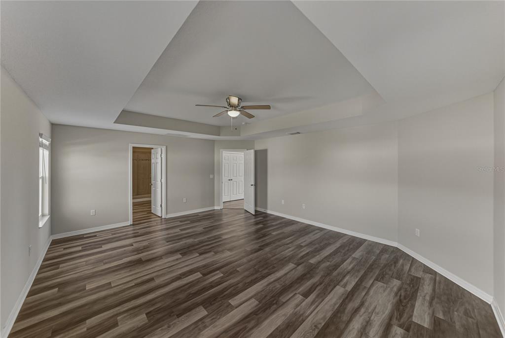 7628 Surf Reed Way Wesley Chapel, FL 33545 - Photo 33 of 76 a view of an empty room with wooden floor and a ceiling fan