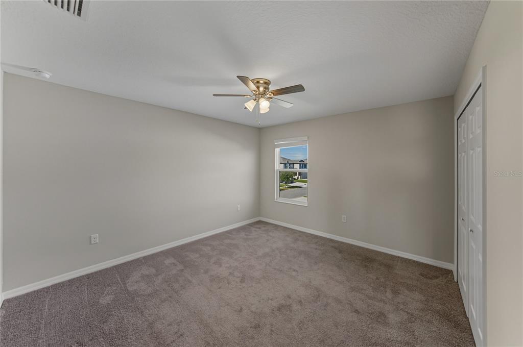 7628 Surf Reed Way Wesley Chapel, FL 33545 - Photo 47 of 76 an empty room with windows and fan