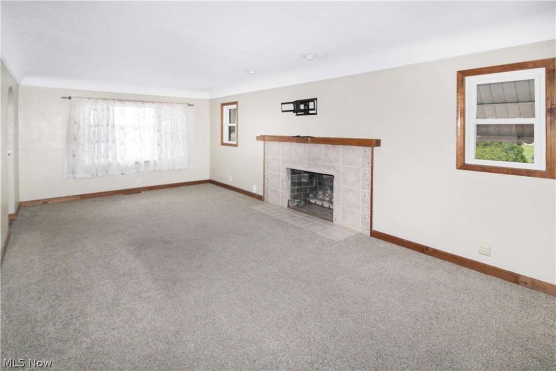 1036 West Fremont Road Port Clinton, OH 43452 - Photo 11 of 32 Unfurnished living room with light carpet, plenty of natural light, and a fireplace