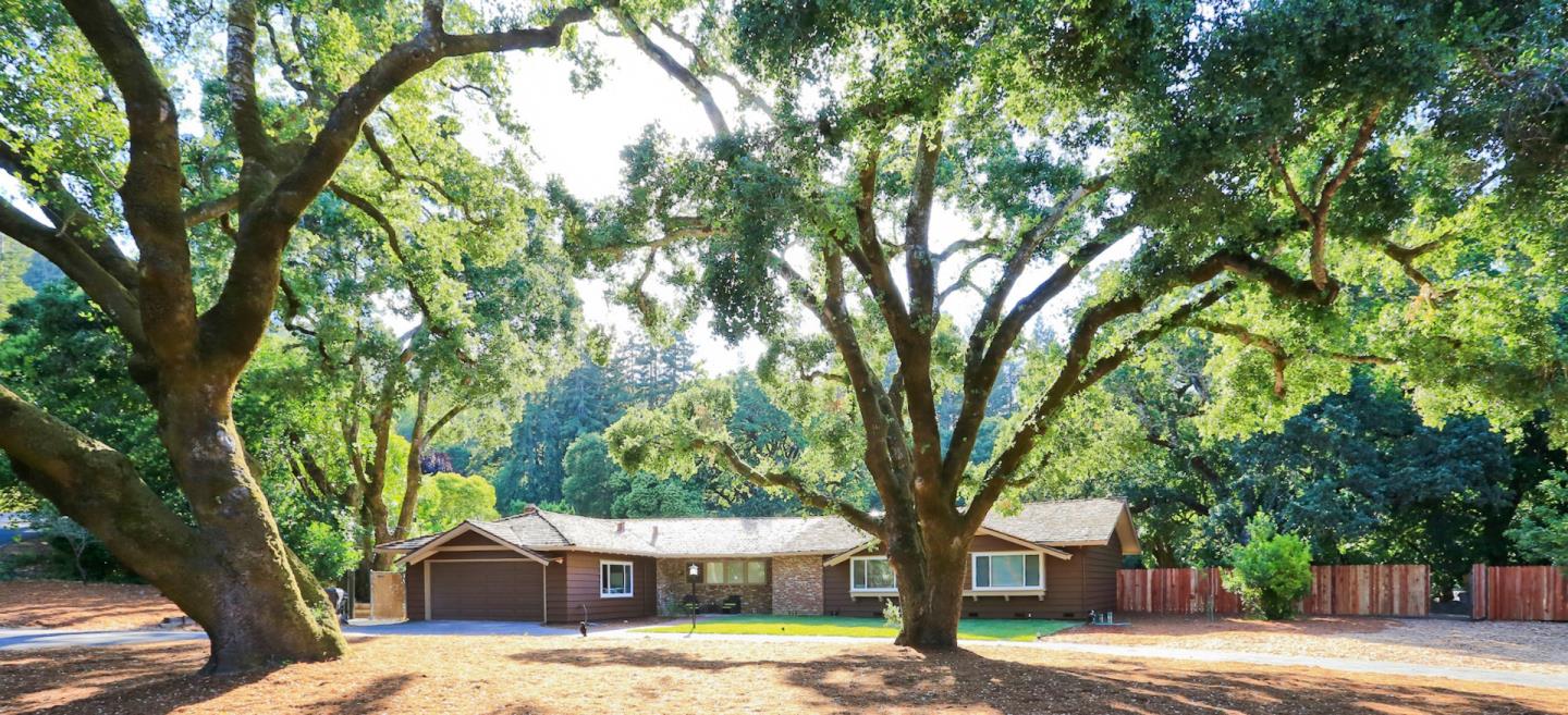 a front view of a house with a yard and large trees