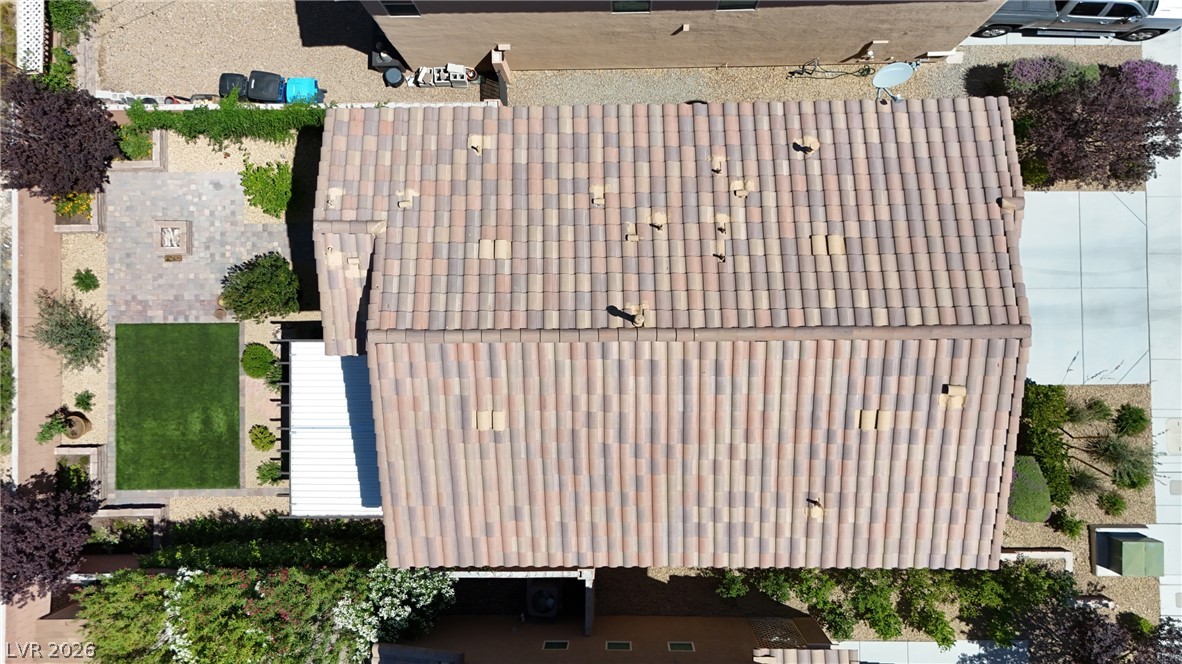 891 Earth Luster Road Las Vegas, NV 89178 - Photo 41 of 48 An aerial perspective showcases the home's tiled roof and a meticulously landscaped yard with a fire pit area.