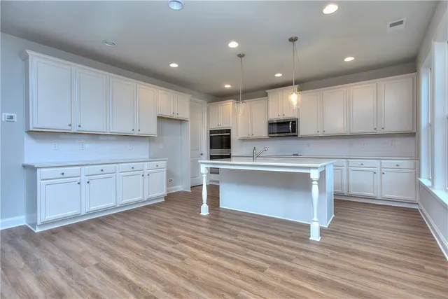 a kitchen with stainless steel appliances granite countertop a stove a sink and white cabinets