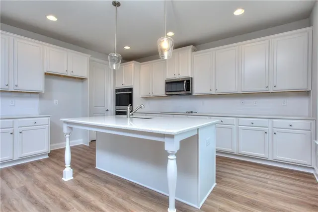 a kitchen with kitchen island granite countertop a sink appliances and cabinets
