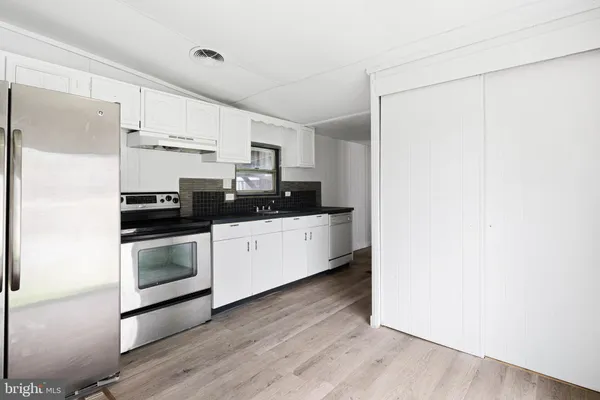 a kitchen with stainless steel appliances a refrigerator sink and white cabinets