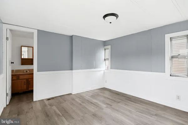 an empty room with wooden floor and a ceiling fan