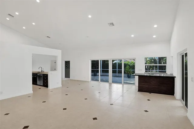 a large white kitchen with granite countertop a stove top oven a sink a barbeque and a window