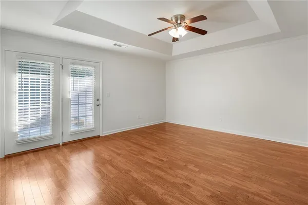 a view of empty room with wooden floor and fan