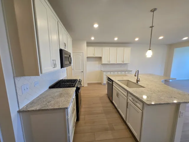 a large kitchen with stainless steel appliances granite countertop a sink a stove and a refrigerator