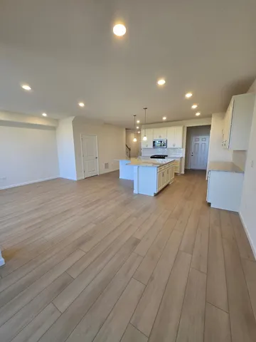 a view of kitchen with kitchen island wooden floor center island and stainless steel appliances