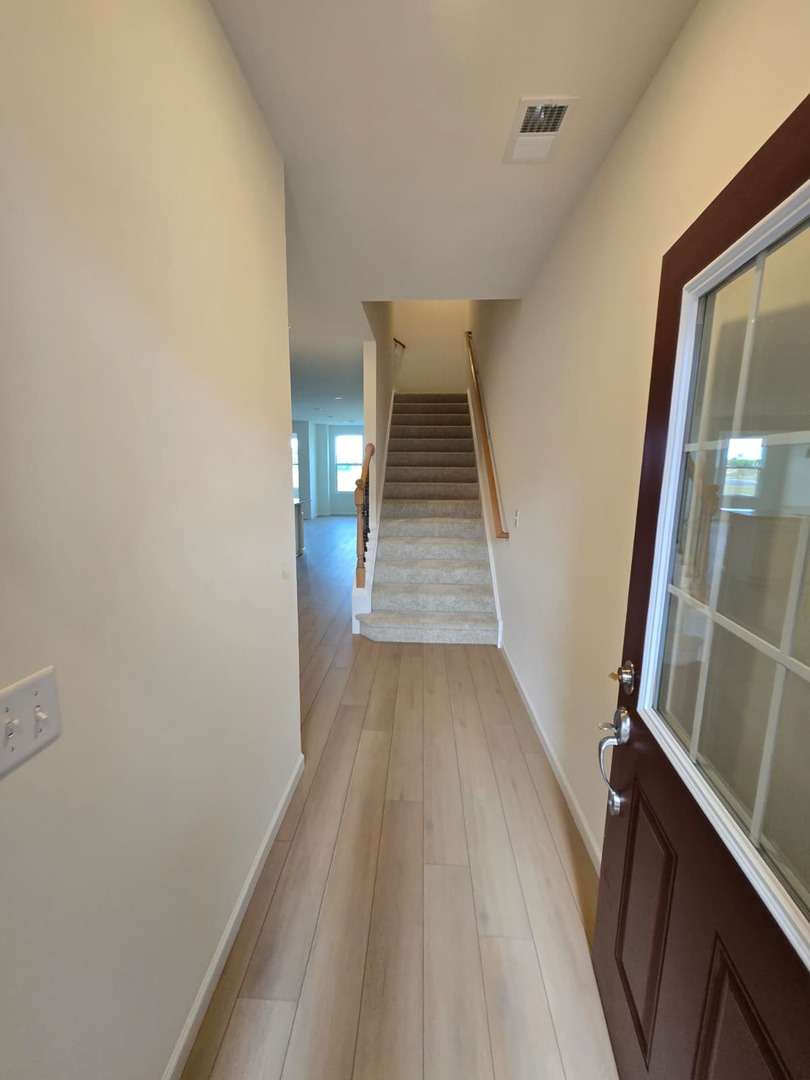 668 Switchgrass Way, Unit 58004 Bolingbrook, IL 60490 - Photo 28 of 31 a view of a hallway with wooden floor and staircase
