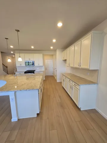 a large kitchen with stainless steel appliances granite countertop a large counter top a sink and a stove