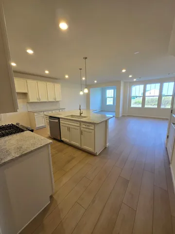 a large kitchen with stainless steel appliances kitchen island a large counter top and a wooden floors