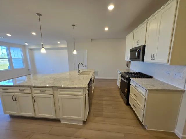 a kitchen with stainless steel appliances granite countertop a sink a stove and a refrigerator