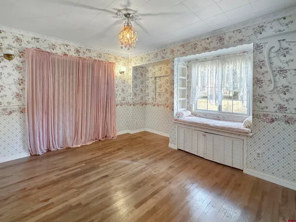 a view of an empty room with a window and wooden floor