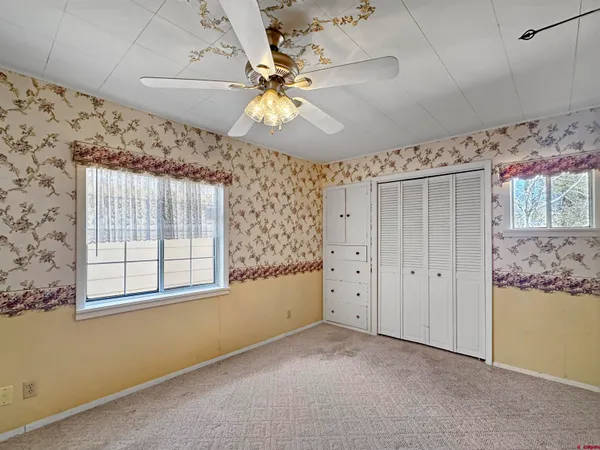 en empty room with windows and ceiling fan
