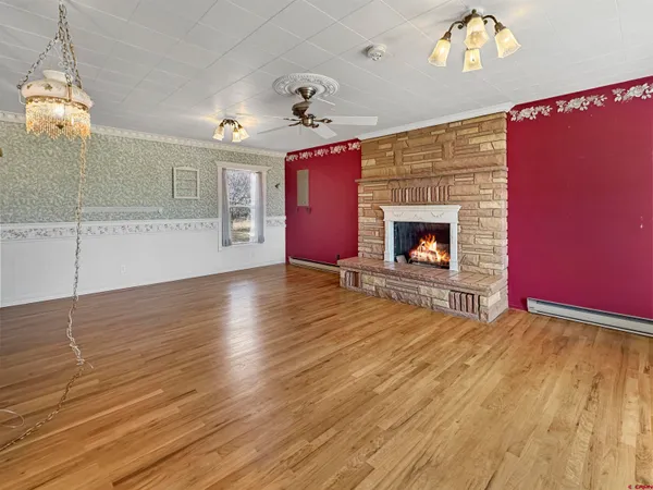 a view of an empty room with wooden floor fireplace and a window