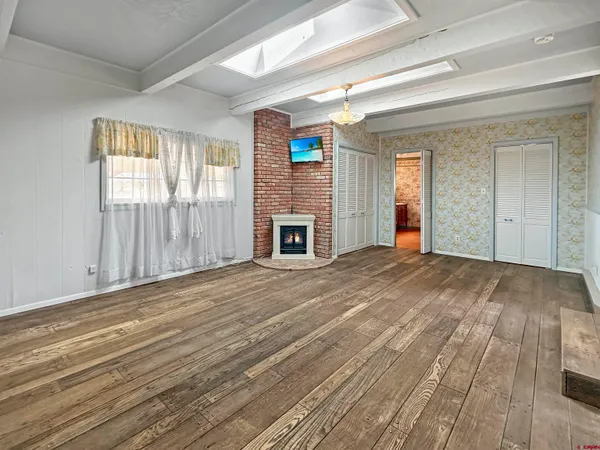 an empty room with wooden floor fireplace and windows