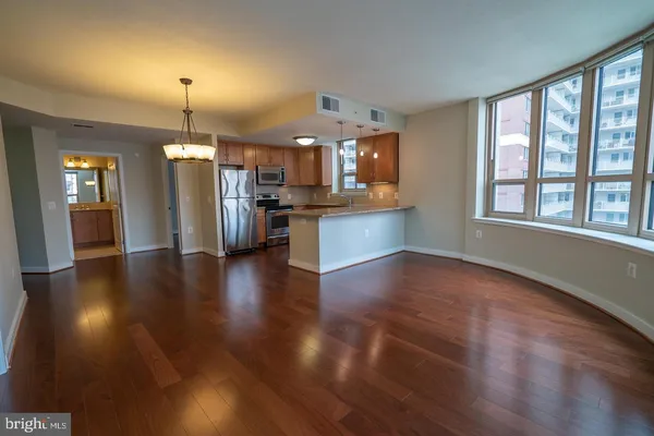 an open kitchen with stainless steel appliances granite countertop a refrigerator stove a dining table and chairs with wooden floor