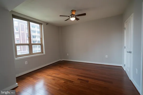 a view of an empty room with wooden floor and a window