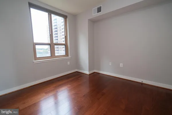 an empty room with wooden floor and windows