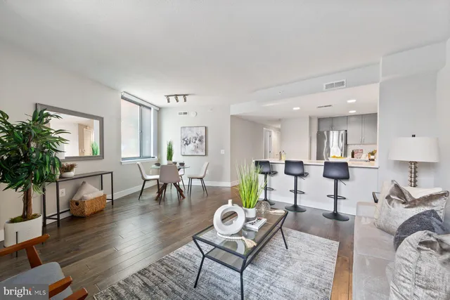 a living room with furniture and a dining table with wooden floor