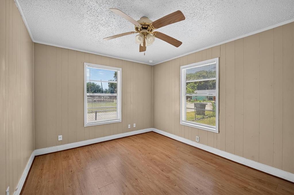 4450 Percy Street Lancaster, TX 75134 - Photo 15 of 18 Room featuring wood-finish flooring, two large windows, a ceiling fan with light fixture, and vertical paneling walls