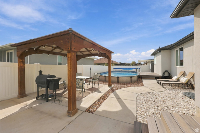 615 West 1870th Street South Payson, UT 84651 - Photo 26 of 31 Outdoor living area featuring a wood-finish pergola, concrete patio, above-ground pool with surrounding deck, and decorative gravel landscaping