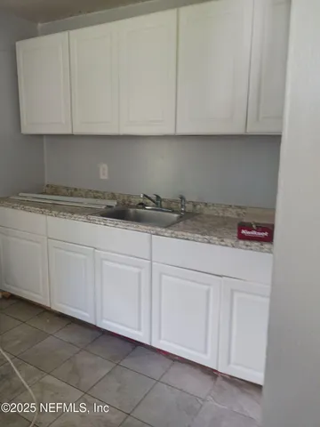a kitchen with granite countertop white cabinets and a hard wood floors