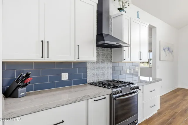 a kitchen with stainless steel appliances granite countertop a stove and a white cabinets