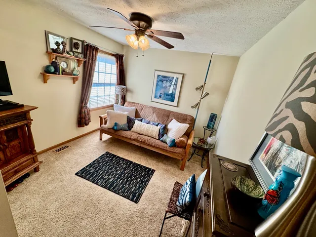 a living room with furniture a flat screen tv and a refrigerator