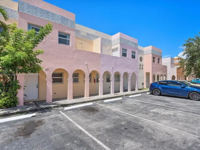 a view of a blue house with large windows and a car parked in front of it