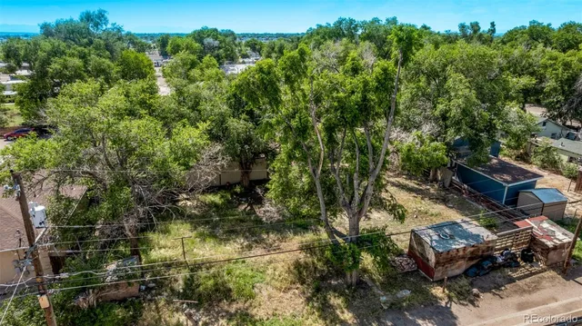an aerial view of a residential houses with outdoor space and trees