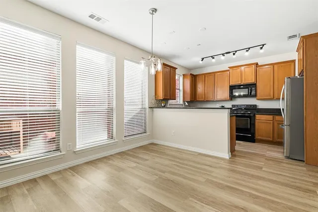 a kitchen with stainless steel appliances granite countertop a refrigerator a sink dishwasher a stove and a refrigerator