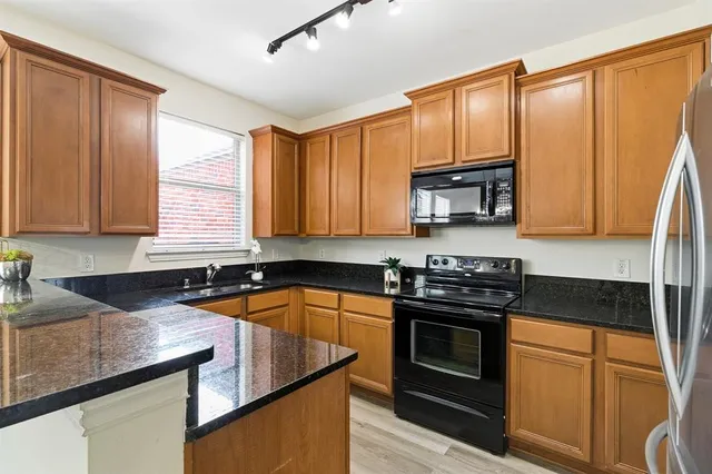 a kitchen with granite countertop a stove sink and microwave