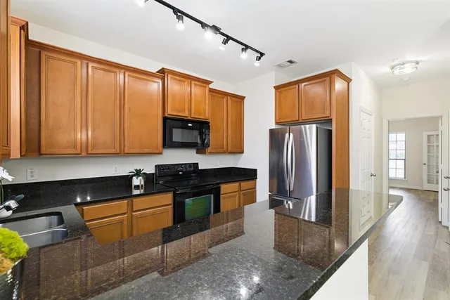 a kitchen with stainless steel appliances granite countertop a refrigerator a stove top oven and sink