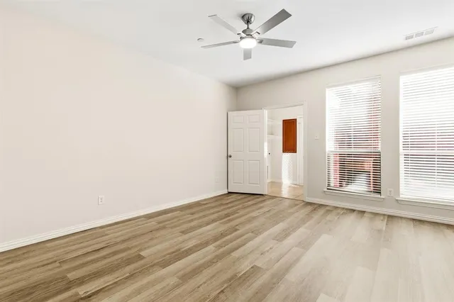 a view of an empty room with a window and wooden floor