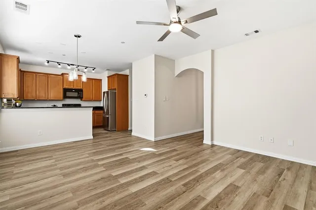 a view of a kitchen with a refrigerator a ceiling fan and wooden floor