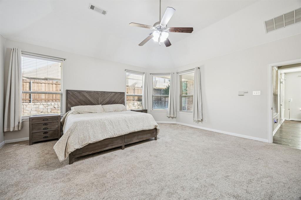 1013 Knoxbridge Road Forney, TX 75126 - Photo 16 of 39 a bedroom with a large bed a chandelier and windows