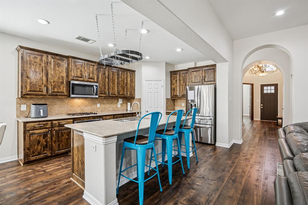 1013 Knoxbridge Road Forney, TX 75126 - Photo 3 of 39 a kitchen with stainless steel appliances granite countertop a stove cabinets and wooden floor