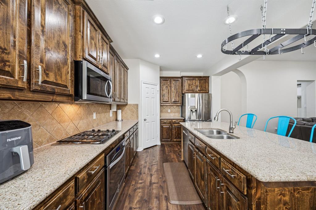 1013 Knoxbridge Road Forney, TX 75126 - Photo 5 of 39 a kitchen with stainless steel appliances a sink a stove top oven a counter space and cabinets