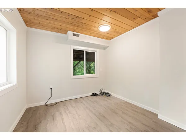 a view of an empty room with a window and wooden floor