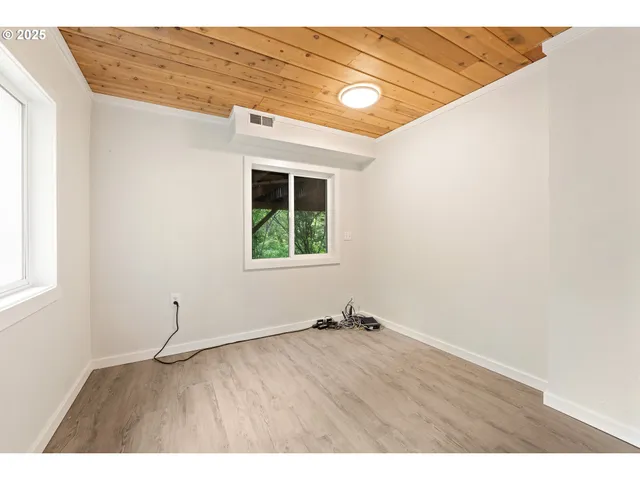 a view of an empty room with a window and wooden floor