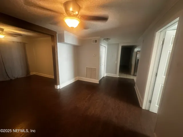 a view of an empty room with wooden floor and a window