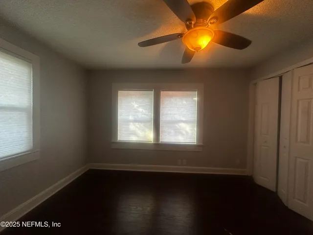 an empty room with wooden floor and windows