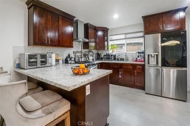 a kitchen with stainless steel appliances granite countertop a sink a stove and a wooden cabinets
