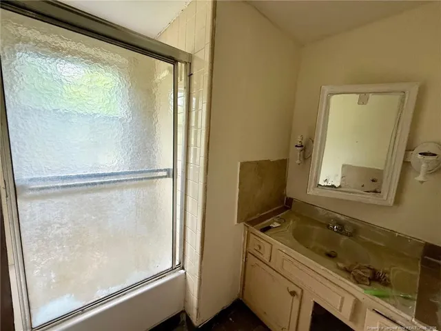 a bathroom with a granite countertop sink mirror and a shower