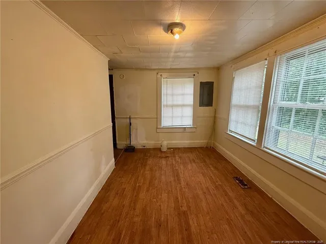 an empty room with wooden floor and windows