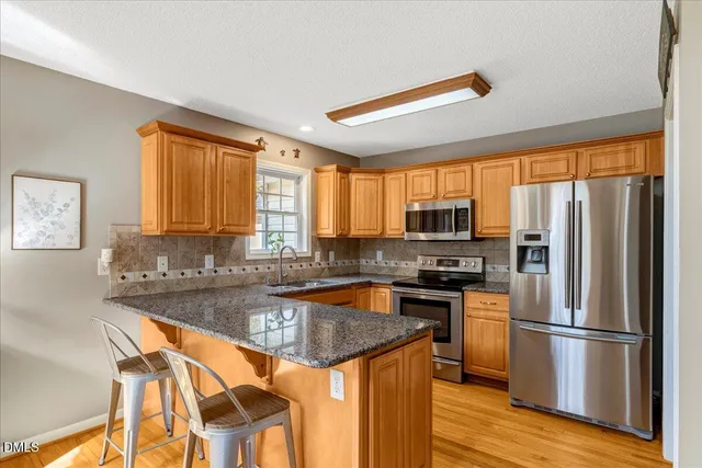 a kitchen with stainless steel appliances granite countertop a refrigerator a stove top oven a sink and dishwasher
